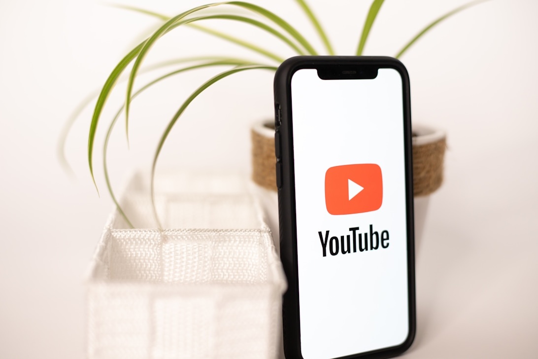 En smartphone med en logotyp på skärmen vilar i en hållare på ett skrivbord, vilket illustrerar hur tekniska profilprodukter blir en del av vardagen.